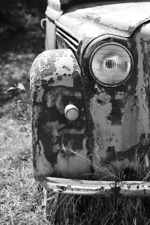 Free A detailed black and white close-up of a vintage rusty car's front end. Stock Photo
