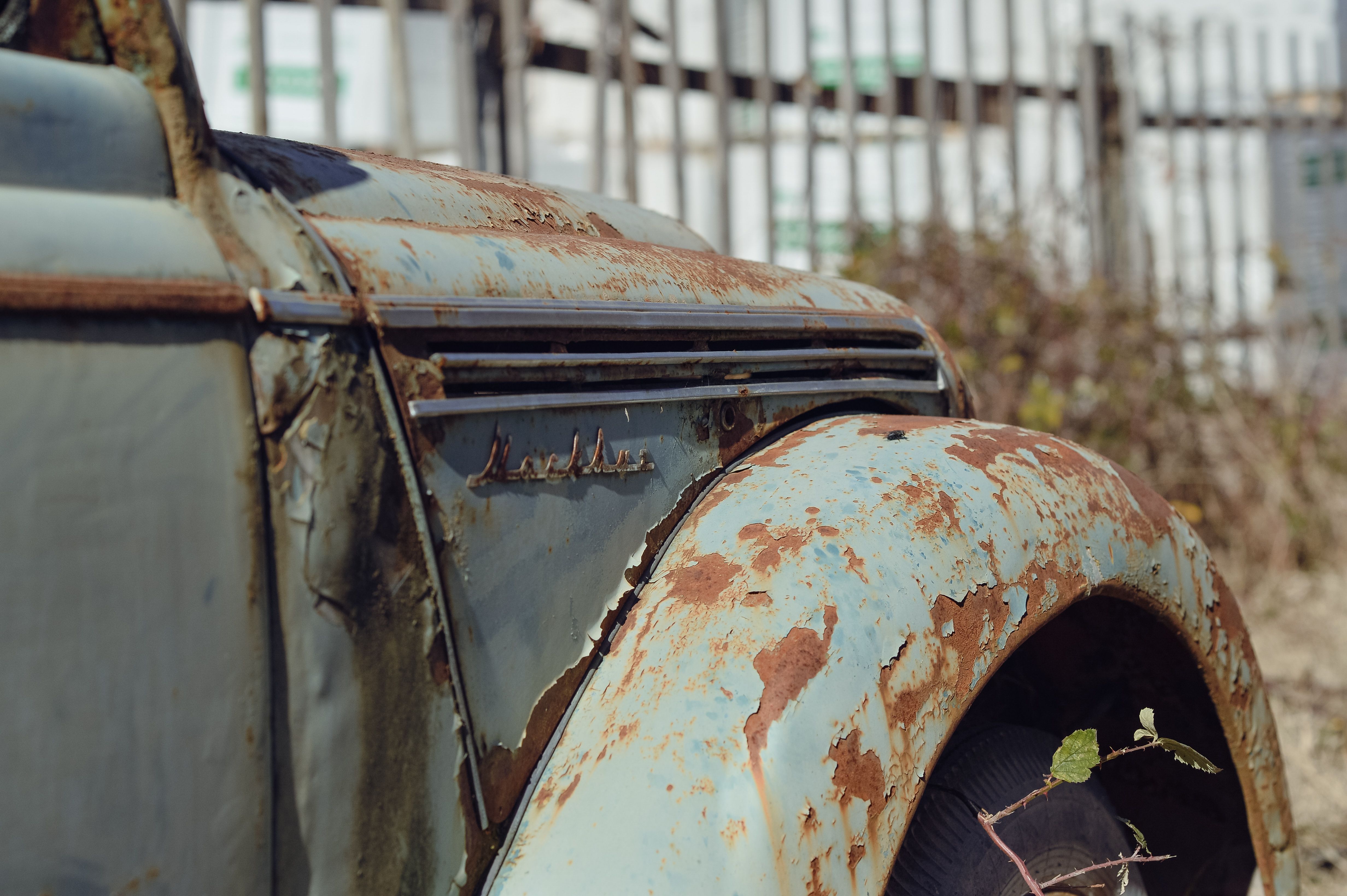 A detailed shot of an old, rusted car outdoors, showcasing vintage textures and decay.