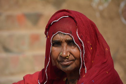 A dignified portrait of an Indian woman in a red saree with intricate embroidery, showcasing cultural heritage.