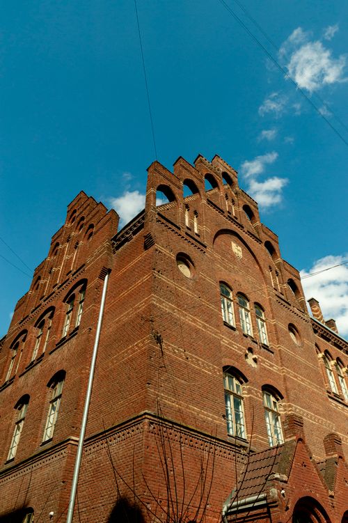 Free Elevated view of a historic red brick building in Lviv, showcasing unique architectural features against a clear blue sky. Stock Photo
