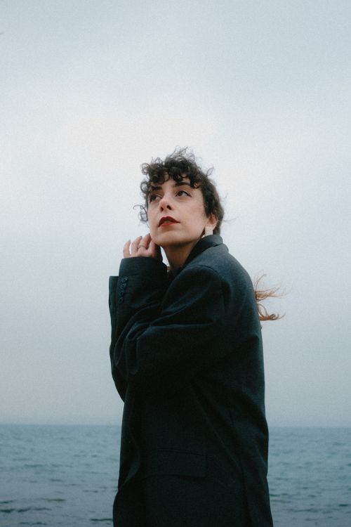 Free A woman in a black coat stands by the sea in Istanbul, looking thoughtful under a gloomy sky. Stock Photo