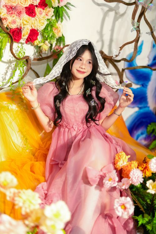 Free Charming scene of a woman in a pink dress amidst vibrant flowers and whimsical decor. Stock Photo
