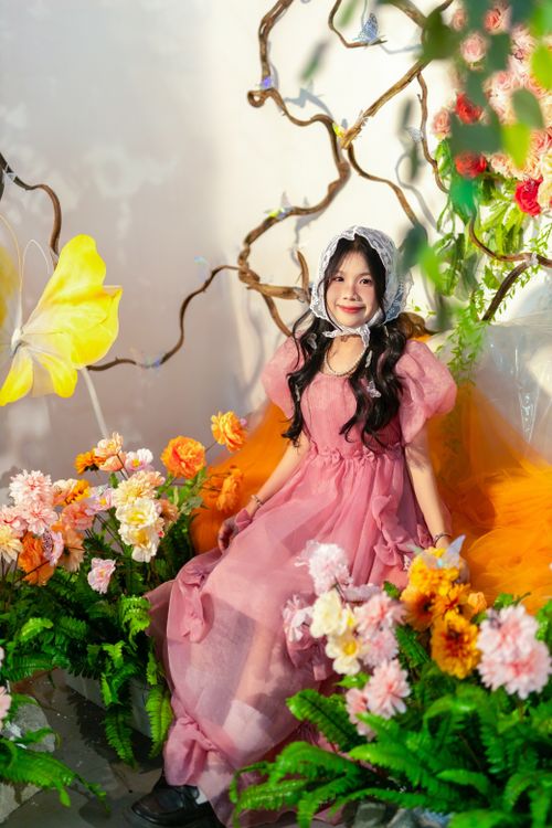 Free Charming girl in a pink dress amidst vibrant flowers and delicate sunlight. Stock Photo