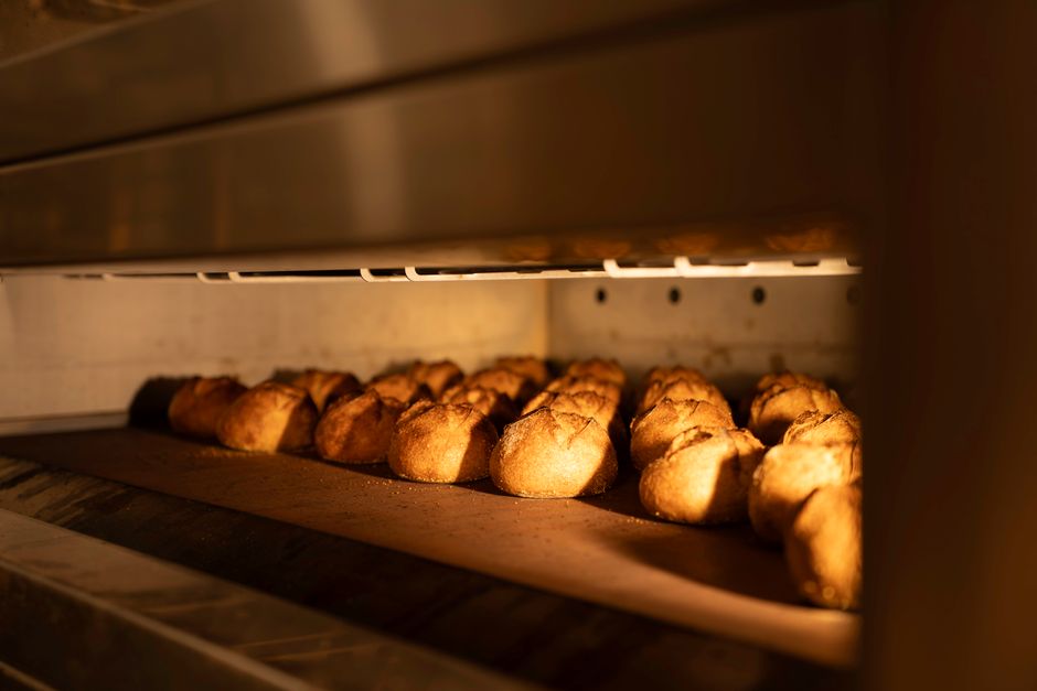 Golden artisan bread loaves baking in a commercial oven, emitting a warm glow.