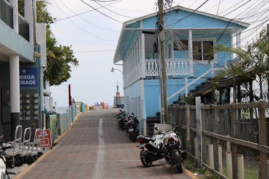 Picturesque street featuring a blue house and parked motorbikes in Utila, Honduras.