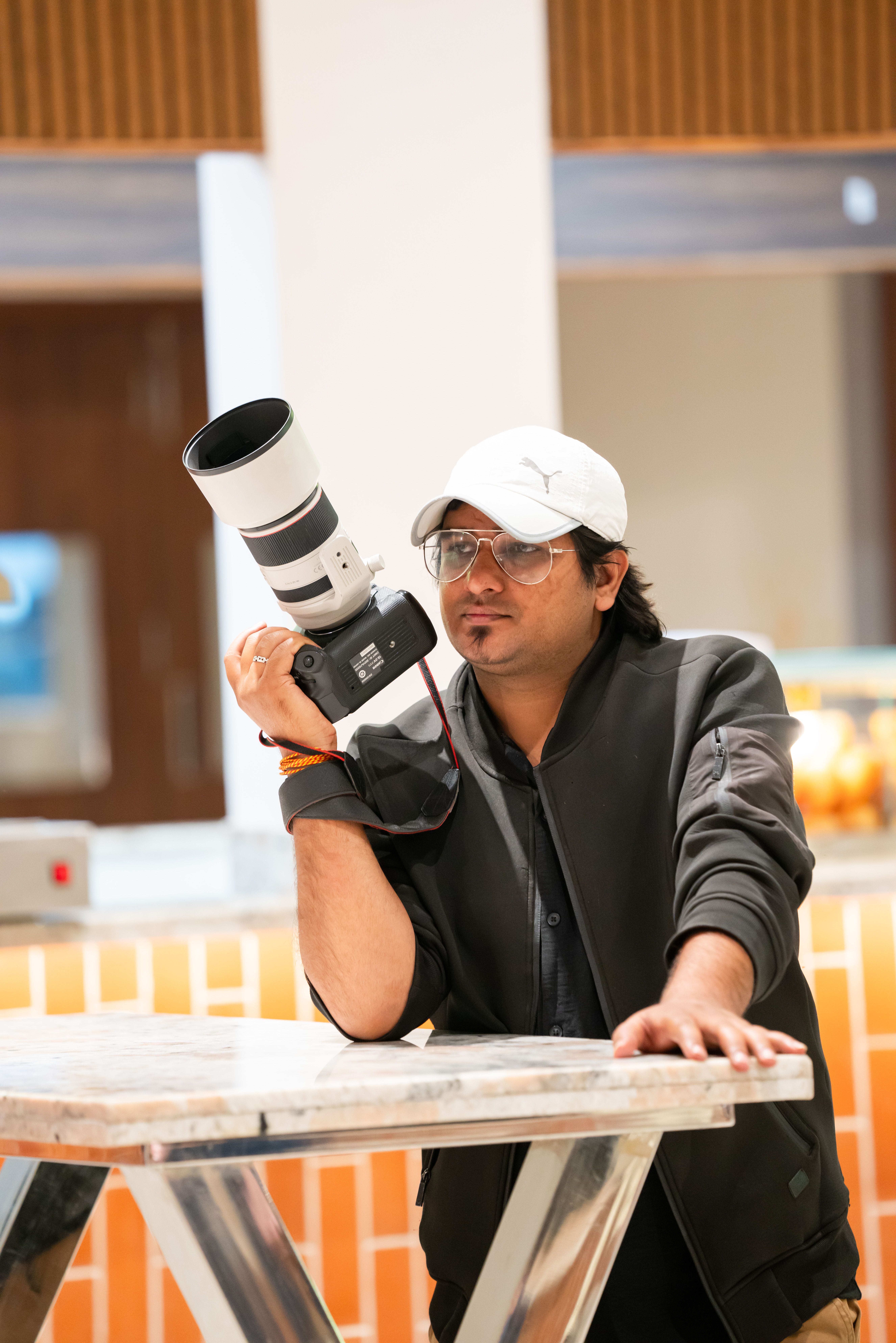 Casual portrait of a young male photographer holding a camera indoors.