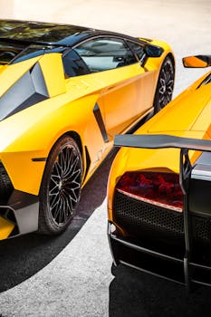 Close-up of two elegant yellow sports cars gleaming under the sunny afternoon sun.