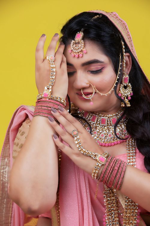 Free Close-up of a woman in pink sari showcasing traditional Indian bridal jewelry. Stock Photo