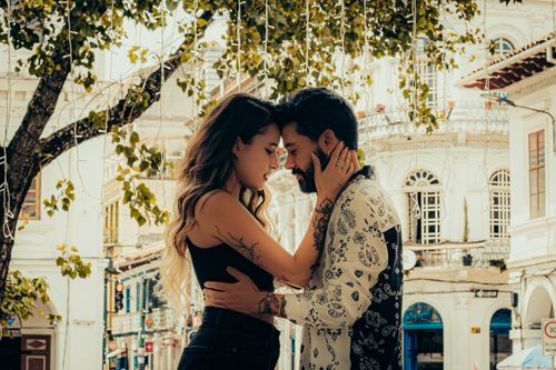 Free A couple shares a heartfelt moment amid a charming Ecuadorian street adorned with trees. Stock Photo