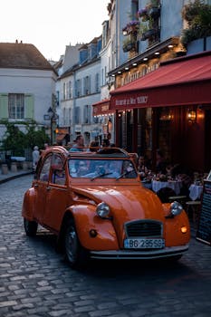 Charming Paris street scene with a vintage orange car near a cozy bistro at dusk.