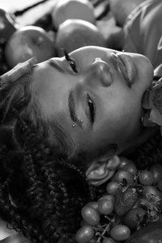 A striking monochrome portrait of a young woman surrounded by fruits from Belo Horizonte, Brazil.