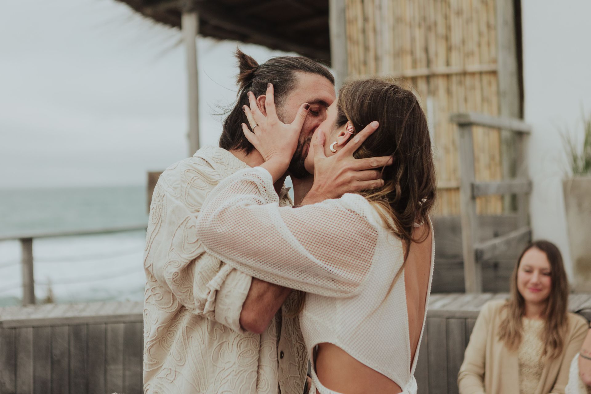 A couple shares a passionate kiss at their beachfront wedding ceremony.