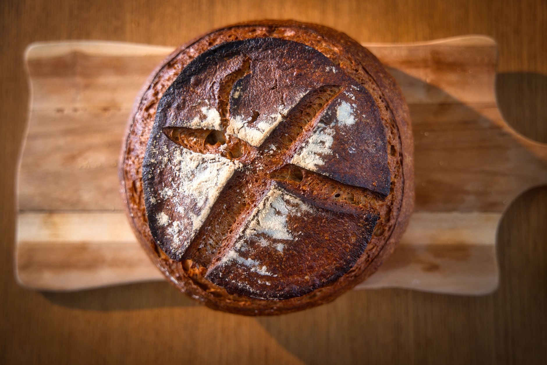 Close-up of a freshly baked artisan bread loaf on a wooden board, showcasing its crusty texture and rustic appeal.