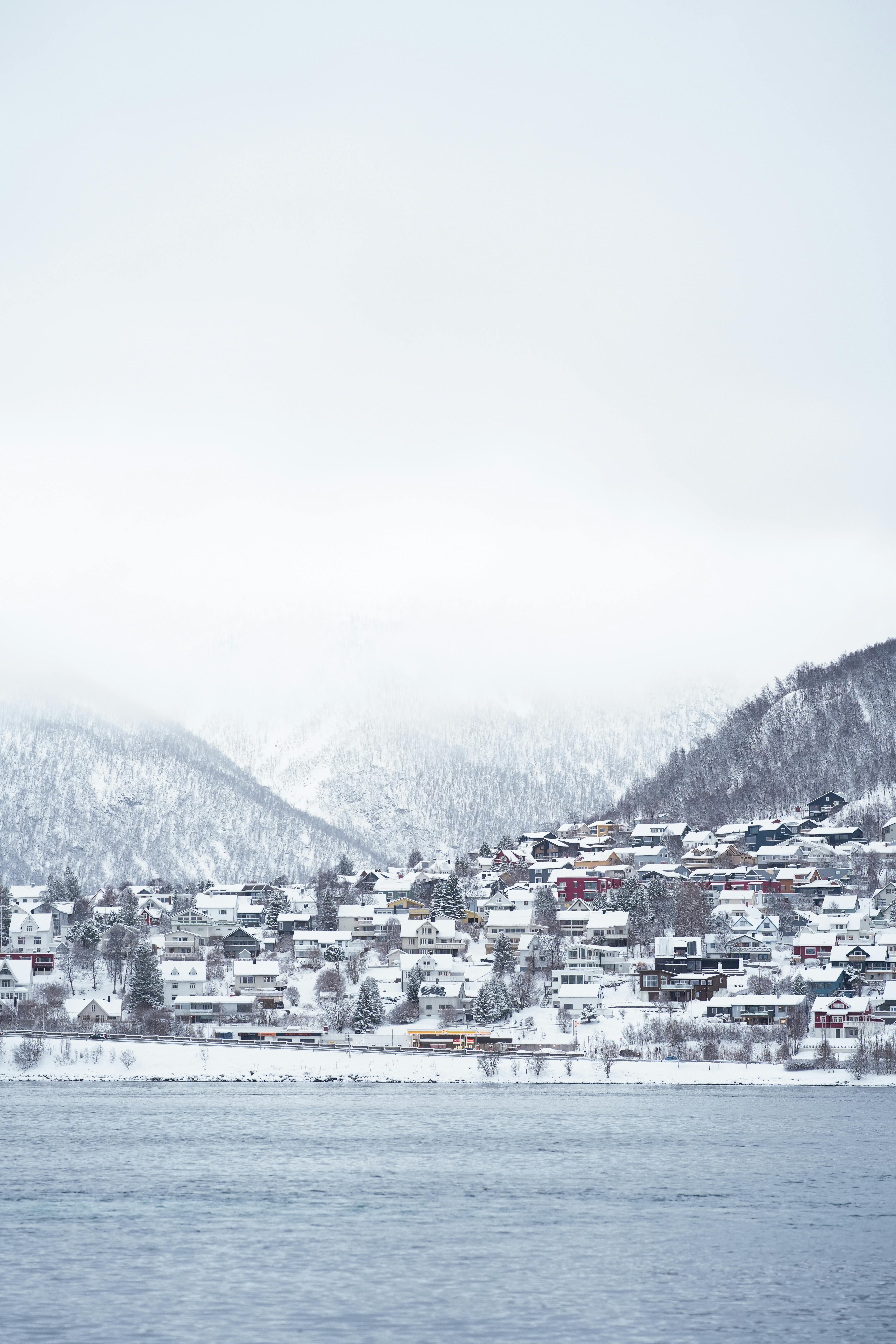 Wintery Tromsø townscape with snowy mountains and houses by the Arctic Ocean.
