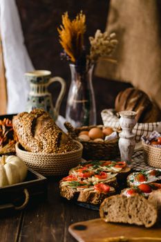 Assorted breads with vegetables and decor on a rustic table setting.