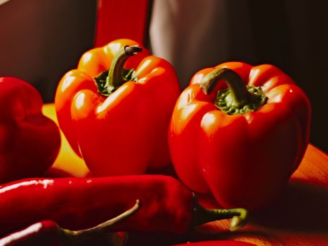Vibrant red bell peppers on a rustic wooden surface, emphasizing freshness and color.