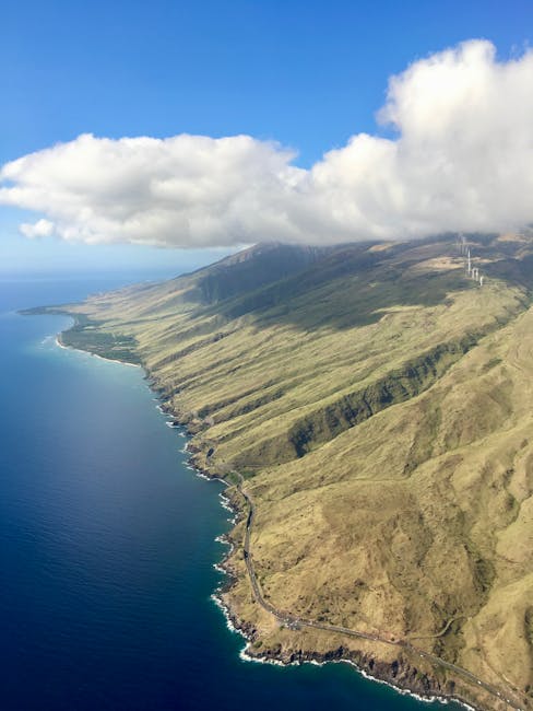 Photo by Pred Sek Stunning aerial view of Maui's dramatic coastline under a blue sky with clouds.
