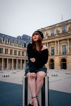 A fashionable woman poses at Palais Royal in Paris, capturing the elegance of the city.