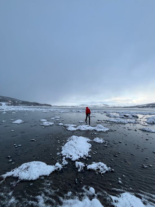 Free Person in red jacket exploring a frozen lake in Norway's winter landscape. Stock Photo