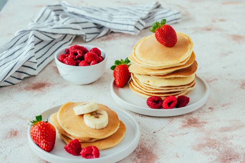 Free A delightful stack of pancakes with strawberries and raspberries, perfect for a cozy breakfast. Stock Photo