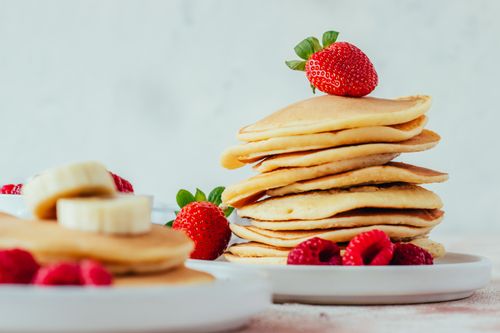 Free A stack of fluffy pancakes adorned with fresh strawberries and raspberries, perfect for breakfast. Stock Photo