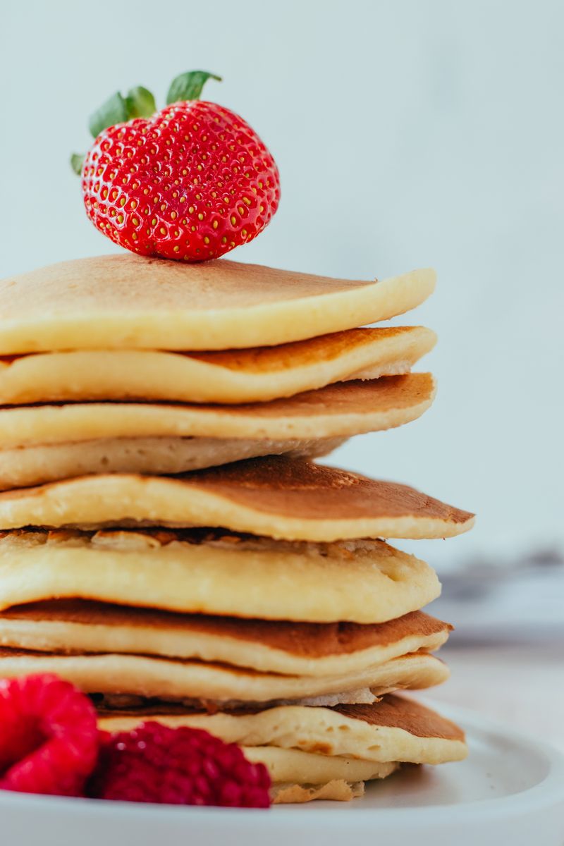 Tall stack of pancakes crowned with a strawberry