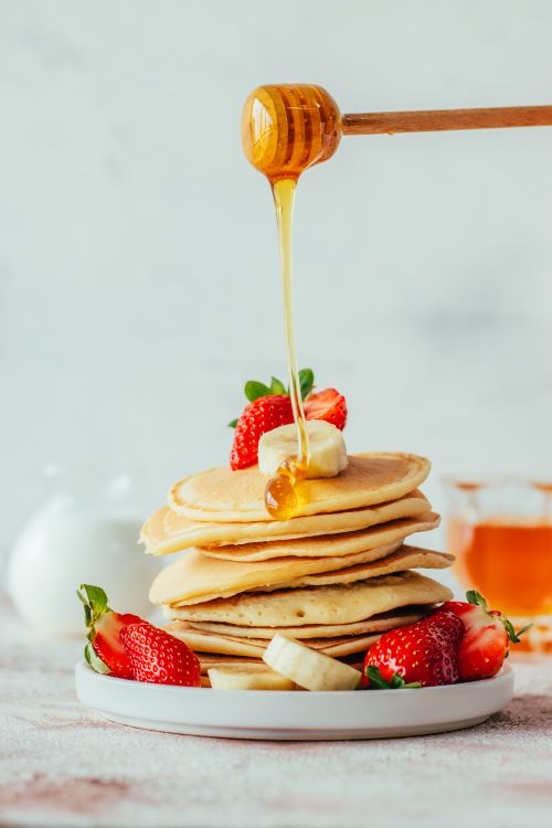Free A delicious stack of pancakes drizzled with honey, garnished with fresh strawberries. Stock Photo