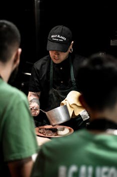 Chef in a professional kitchen preparing a gourmet dish with focused attention.