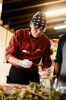 Chef preparing dish with precision in a restaurant kitchen setting.