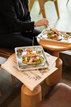 Tasty sandwich with fresh greens and condiments on cafe table.