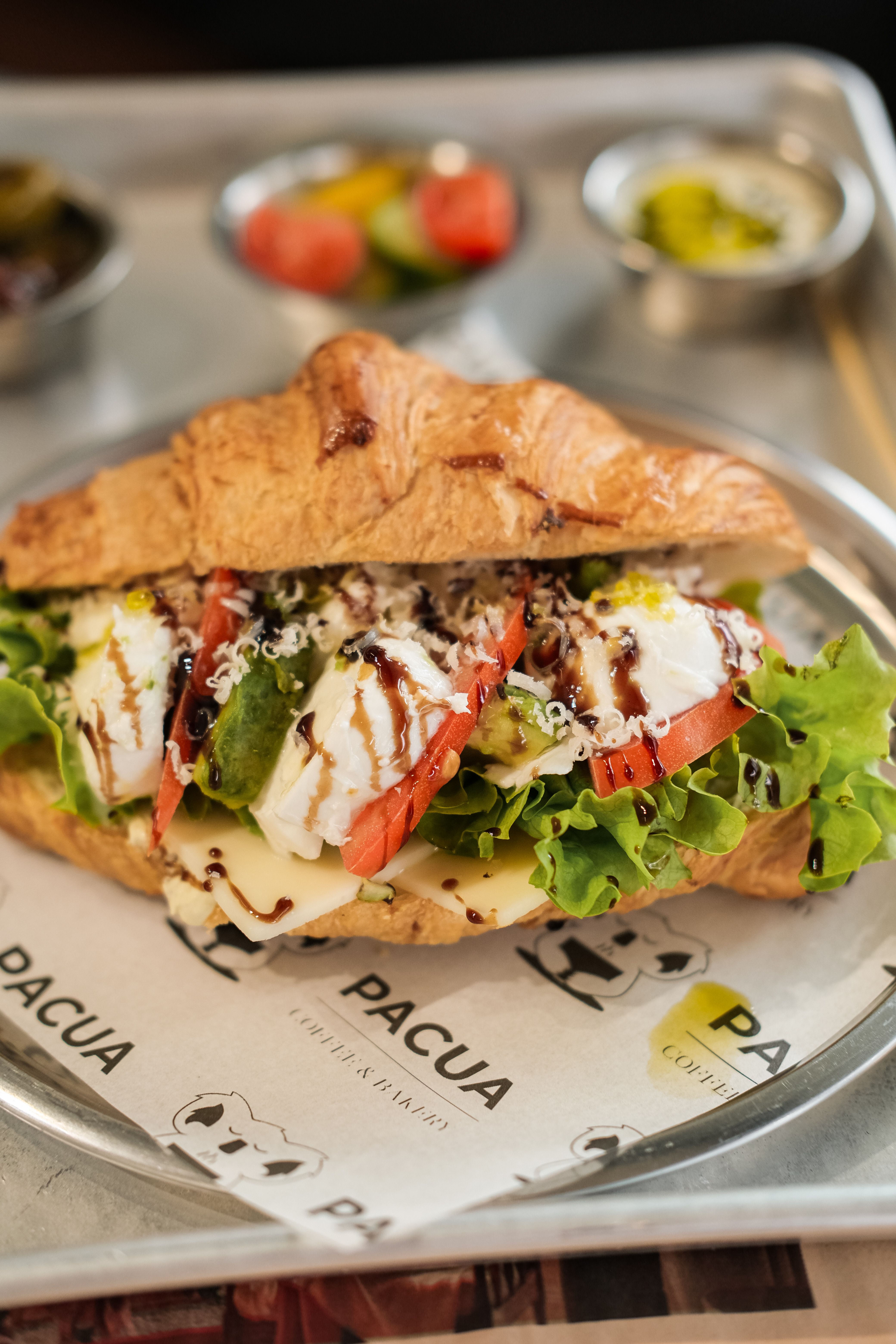 Close-up of a gourmet caprese sandwich with fresh ingredients on a croissant.