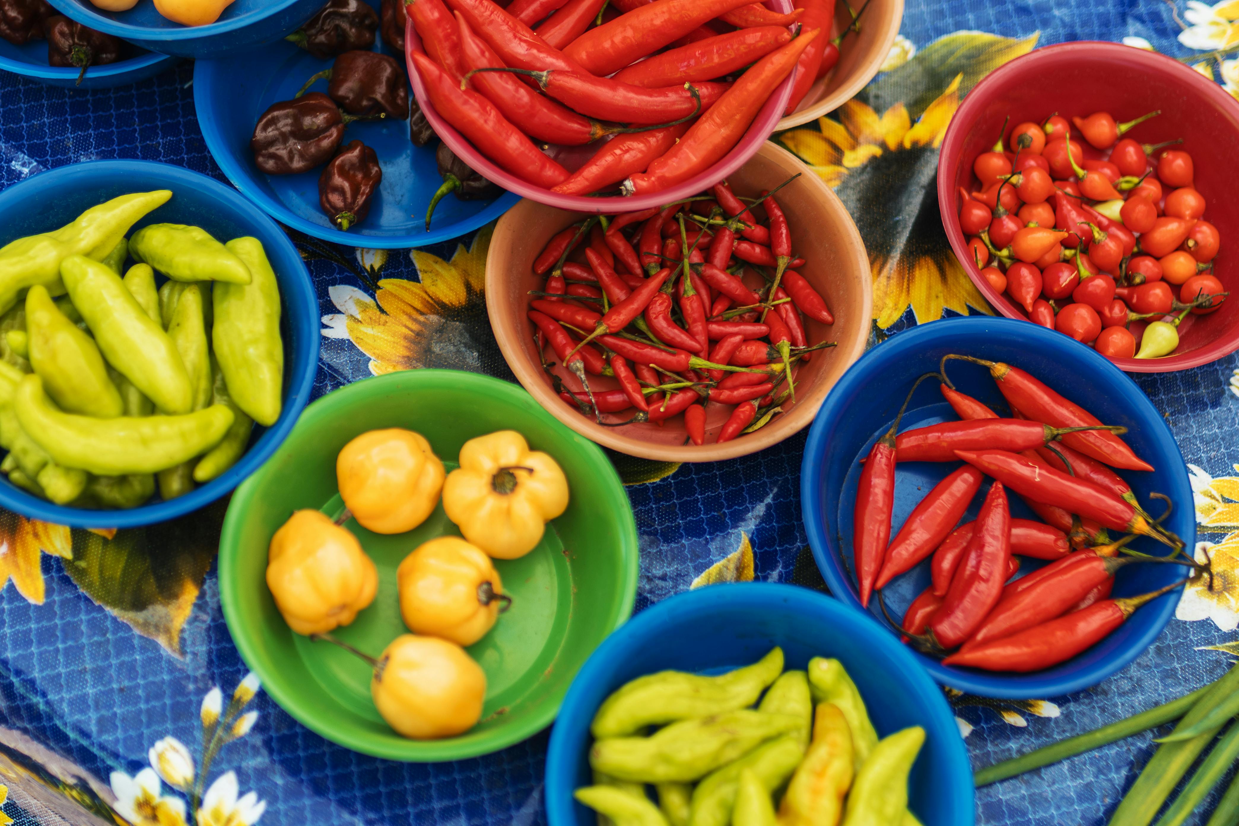 A top-down view of assorted chili peppers in vibrant bowls, showcasing a variety of colors and shapes.