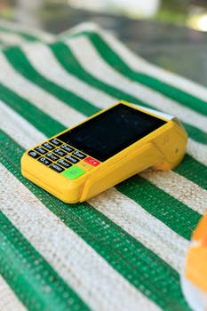 A vibrant yellow card reader resting on a green and white striped surface, ready for transactions.