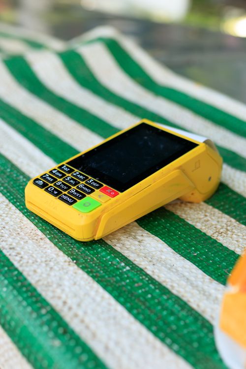 Free A vibrant yellow card reader resting on a green and white striped surface, ready for transactions. Stock Photo