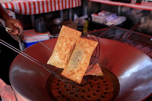 Freshly fried crispy pastries in hot oil, showcasing vibrant street food culture.