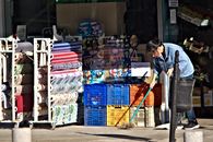 A woman sweeps the sidewalk outside a busy shop in Seville, Spain.