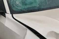 Detailed view of a car with a shattered windshield and front damage, highlighting accident details.
