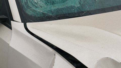 Detailed view of a car with a shattered windshield and front damage, highlighting accident details.