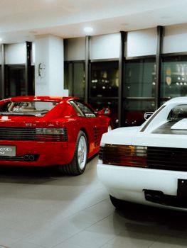 Red and white luxury sports cars displayed indoors, showcasing elegance and classic design.