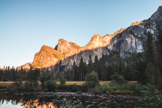 Sunset over Yosemite National Park's majestic mountains reflecting in a serene river.