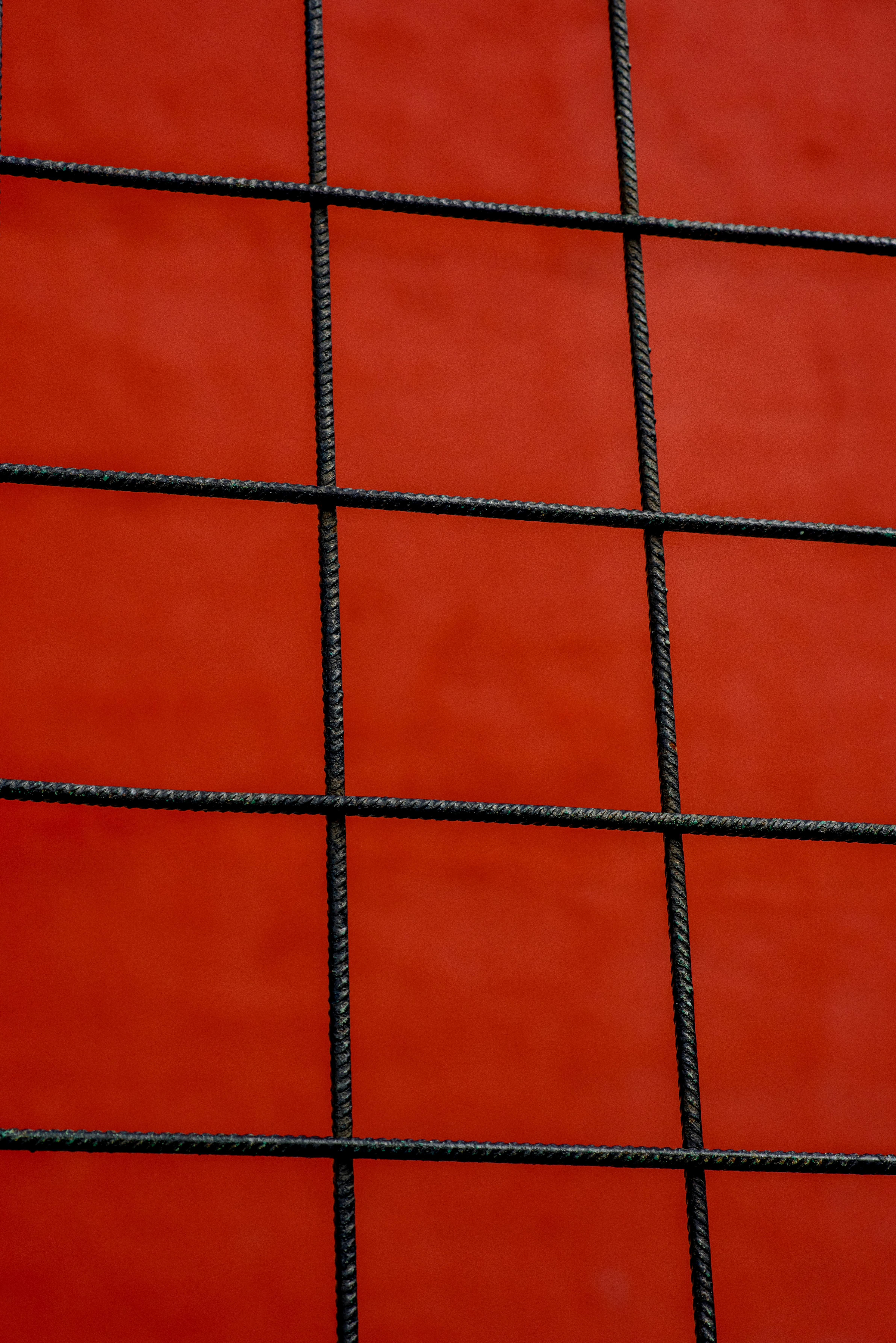 A minimalist wire grid against a vibrant red backdrop, creating a bold abstract design.