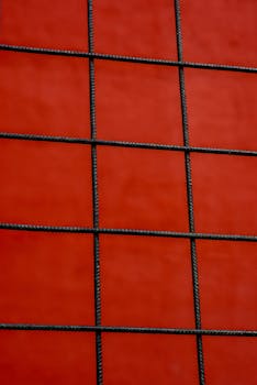 A minimalist wire grid against a vibrant red backdrop, creating a bold abstract design.