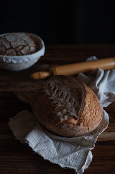 A rustic loaf of artisan bread with intricate scoring on a wooden table, perfect for culinary themes.