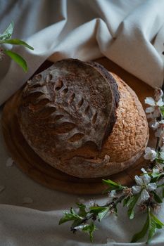 Artisan sourdough bread with intricate leaf design, surrounded by blossoms.