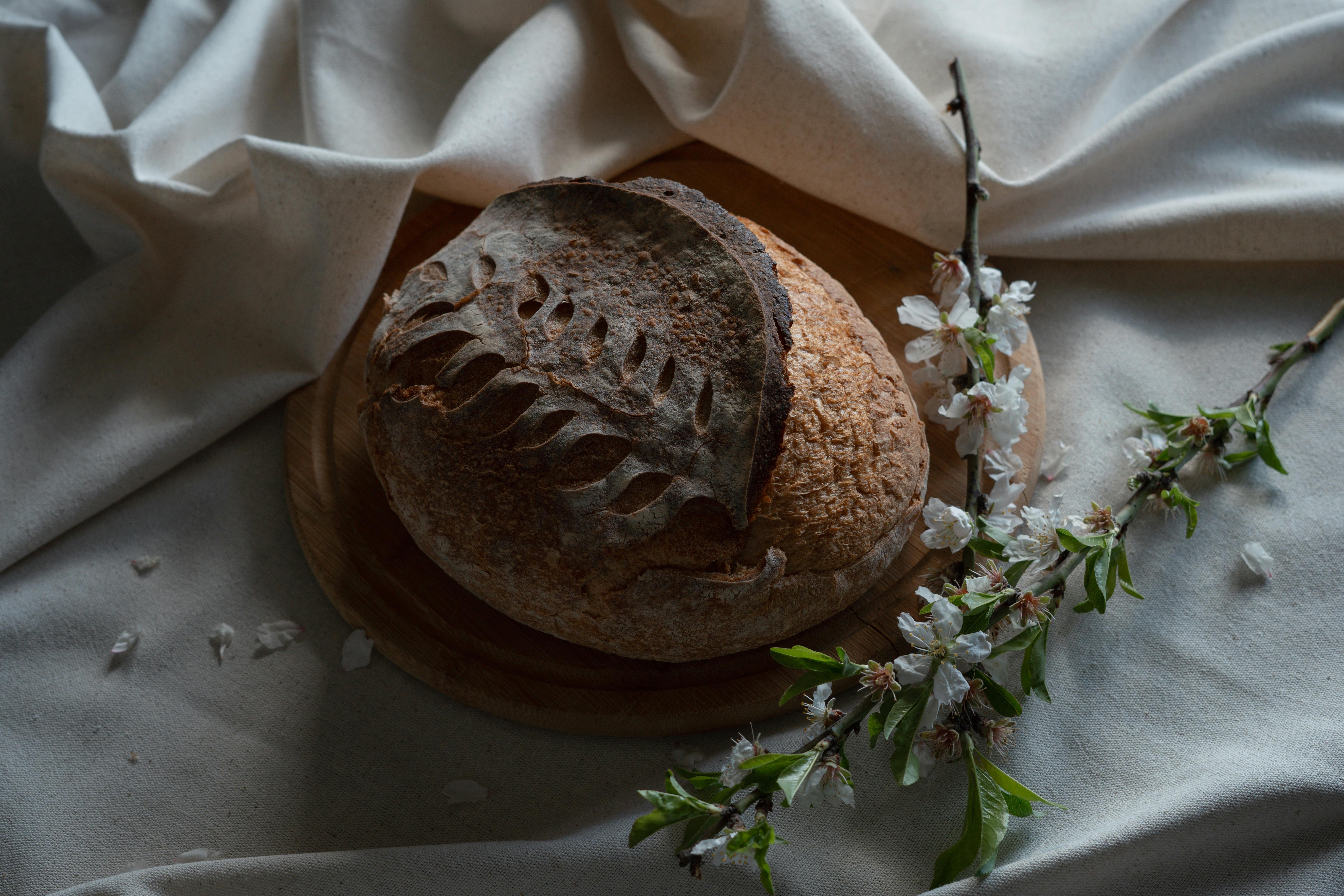 Artistic display of rustic round bread on a wooden plate with spring florals.