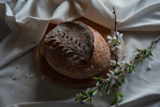Artistic display of rustic round bread on a wooden plate with spring florals.