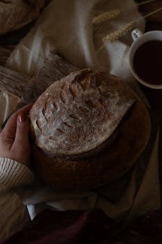 A cozy scene with artisanal bread held by a hand, and a tea cup beside.