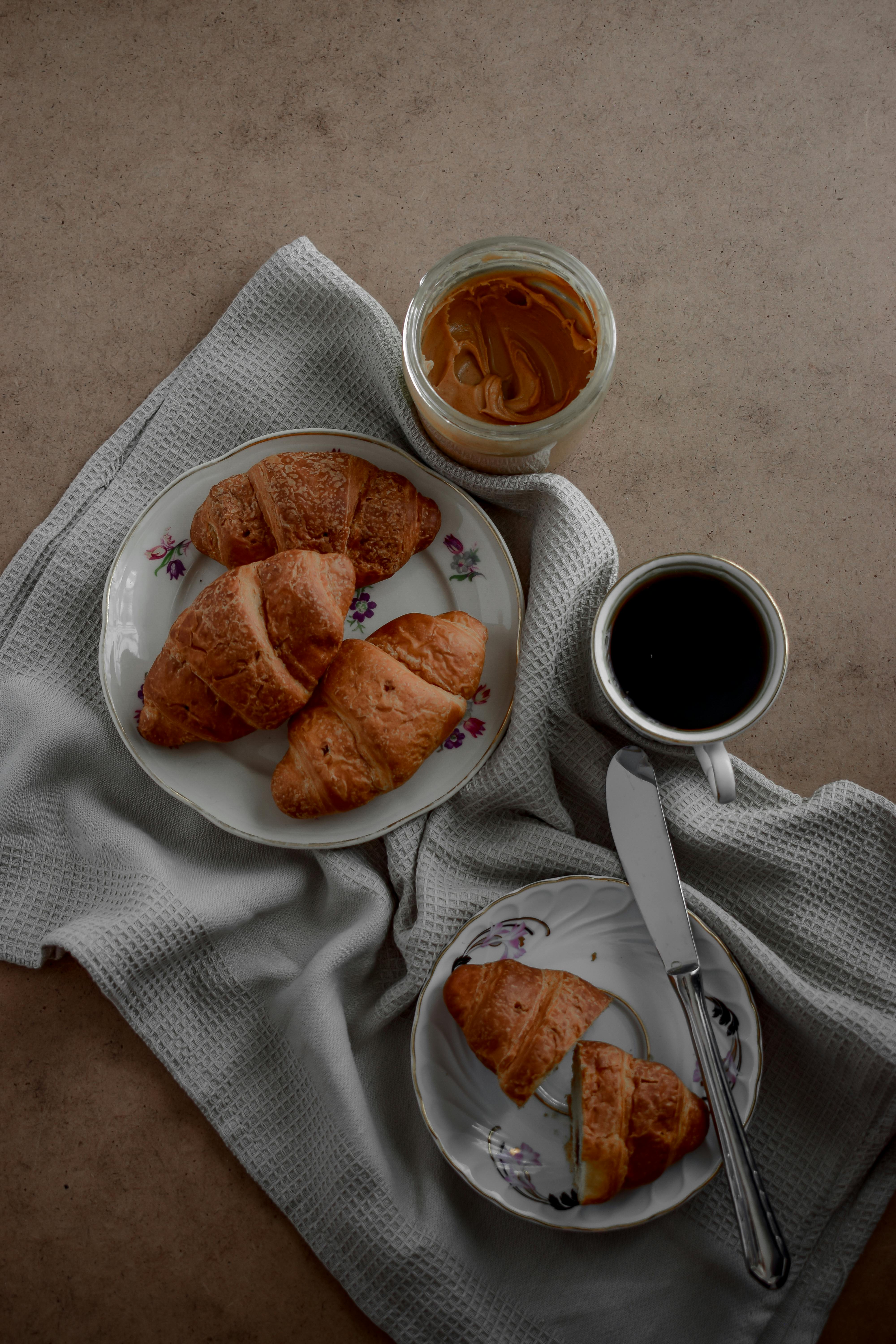 Stylish top view of croissants and a coffee cup on a breakfast table.