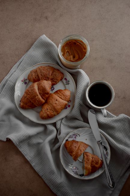 Stylish top view of croissants and a coffee cup on a breakfast table.