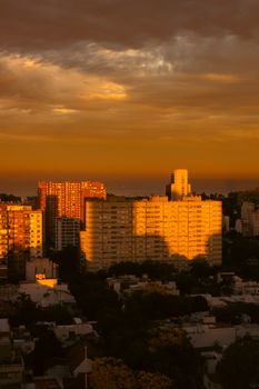 City skyline at sunset with striking orange hues and dramatic cloud formations.
